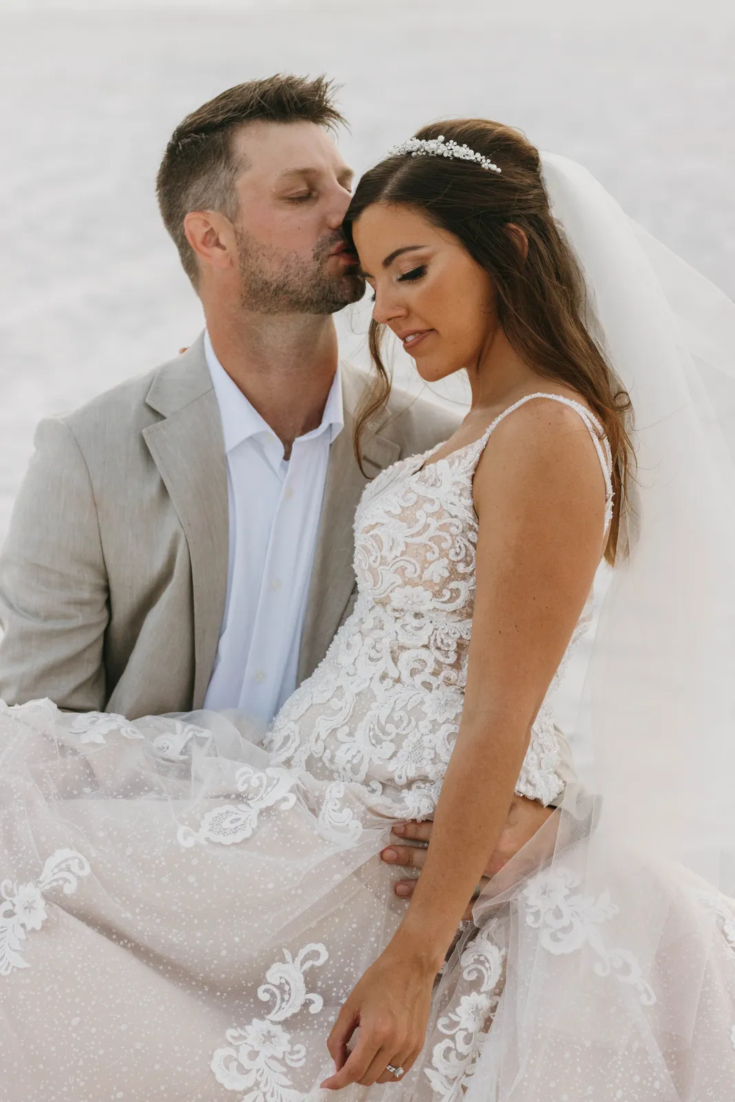 A bride and groom embracing on the beach in soft light